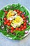 Healthy food on a plate. Rucola, avocado with egg, cherry tomatoes, blue onion. Vegetarian lunch.