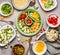 Healthy food preparation: gut colorful vegetables on green plate and bowls with barley seeds and feta