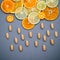 Healthy foods and medicine concept. Pills of vitamin C and various citrus fruits sliced in the shape of cloud and raining. Mixed