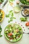 Healthy fresh green salad plate topped with various seeds and berries on light table background with olives oil and ingredients.