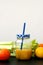 Healthy fresh smoothie drink from green celery, lemon and mandarin orange in glass with straw