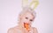 Healthy girl with nibbles a carrot like a hare. Vegan easter bunny eating healthy carrot. Happy easter and spring