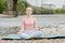 Healthy girl relaxing while meditating and doing yoga exercise in the beautiful nature on the bank of the river