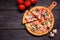 Healthy, gluten free cauliflower crust pizza with tomatoes, mushrooms and spinach. Top down view table scene on dark wood.