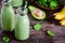 Healthy green smoothie with banana, spinach, avocado and chia seeds in glass bottles