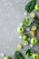 Healthy green smoothie with fresh green fruits, kale and spinach on gray background, top view