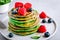 Healthy green spinach pancakes with raspberries, blueberries and honey