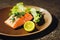 Healthy grilled salmon and salad meal on a round brown plate