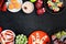 Healthy Halloween fruit treats, top view doouble border over a black stone background with copy space