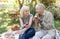 Healthy and happy retirement. Positive elderly spouses sitting on lawn and eating apples, resting in garden