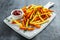 Healthy Homemade Baked Orange Sweet Potato and french Fries with ketchup, salt, pepper on white wooden board