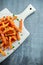 Healthy Homemade Baked Orange Sweet Potato Fries with ketchup, salt, pepper on white wooden board