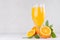 Healthy homemade lemonade - orange juice in wineglass with oranges and green leaves on white wood background.