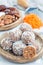 Healthy homemade paleo energy balls with carrot, nuts, dates and coconut flakes, on wooden plate