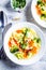 Healthy kids alphabet soup with broccoli, carrot and potato in white plates, top view