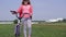 Healthy lifestyle - girl with a bicycle walking on a field near the city