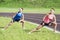 Healthy Lifestyle Ideas and Concepts. Two Young Caucasian Girlfriends in Athletic Sportswear Having Trunk Bending Exercises