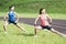 Healthy Lifestyle Ideas and Concepts. Two Young Caucasian Girlfriends in Athletic Sportswear Having Trunk Bending Exercises