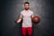 Healthy lifestyle - portrait of attractive muscular caucasian man holding a smartphone and a basketball