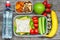 Healthy lunch boxes with sandwich, eggs and fresh vegetables, bottle of water, nuts and fruits