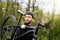 Healthy man bicycler carrying mountain bike while exploring in woods