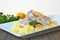 Healthy meal from fish and mashed potatoes with lemon and parsley on white plate on dark brown wooden background