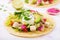 Healthy mexican corn tacos with boiled chicken breast, avocado and watermelon radish