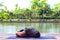 Healthy middle aged asian woman sitting in seated forward bend exercise or paschimottanasana yoga pose in city park at the morning