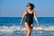 Healthy middle aged woman in sunglasses swimsuit walking along seashore