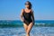 Healthy middle aged woman in sunglasses swimsuit walking along seashore