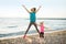 Healthy mother and baby girl jumping on beach