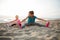 Healthy mother and baby girl stretching on beach