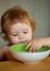 Healthy nutrition for kids. Portrait of cute Caucasian child kid with spoon. Hungry messy baby with plate after eating.