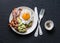 Healthy nutritious breakfast - avocado toast, bacon and fried egg on dark background