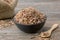 Healthy oak bark in black bowl and sack of dry oak bark on background. Herbal medicine