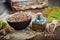 Healthy oak bark in bowl, infusion or tincture bottle, old book, green oak leaves and acorns on wooden table.