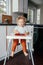 Healthy organic baby food. Caucasian baby boy eating ripe red fruits at home. Funny child kid sitting high chair with fresh ripe