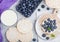 Healthy organic rice cakes with ricotta and fresh blueberries and glass of milk on light stone kitchen background. Top view. Plast