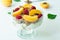 Healthy parfait with greek yoghurt, homemade granola, slices of apricot and raspberries in a glass goblet on a white background.