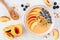 Healthy peach smoothie bowl with blueberries and granola, above view table scene on marble