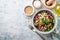 Healthy pearl barley salad with beans, cucumbers, red onion, sunflower seeds, pomegranate and parsley in bowl