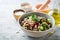 Healthy pearl barley salad with beans, cucumbers, red onion, sunflower seeds, pomegranate and parsley in bowl