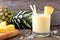 Healthy pineapple smoothie, scene against wood
