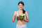 Healthy positive woman in white sportswear with perfect slim body showing thumbs up holding big bowl with fresh vegetable salad,