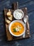 Healthy quinoa carrot soup with feta cheese, seeds and nuts on rustic dark wooden board.