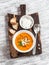 Healthy quinoa carrot soup with feta cheese, seeds and nuts on rustic light wooden board.