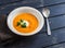 Healthy quinoa carrot soup on rustic light wooden board.