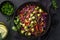 Healthy rainbow cole slow, red cabbage, avocado, carrot and bell pepper salad in black bowl