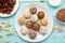 Healthy raw energy balls. Candy vegan balls of dates, nuts and coconut on plate on blue background. Top view, concept of useful