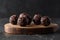 Healthy raw sweets concept. Homemade vegan energy balls with raw buckwheat on wood slab on dark background side view low key